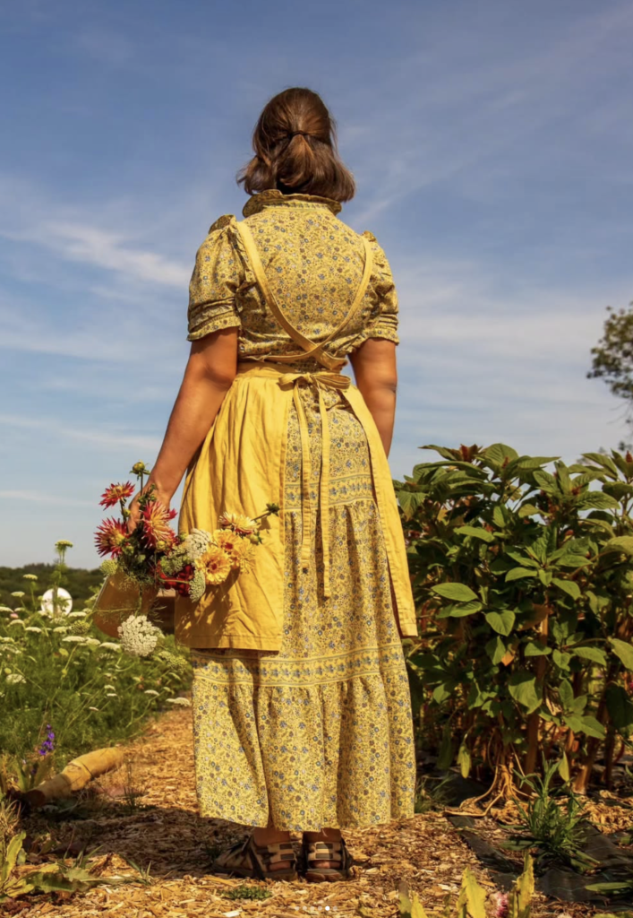 Woman in yellow dress gathers flowers at Folly Oast Flower Farm